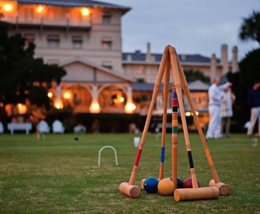 Croquet mallets on the lawn of the Jekyll Island Club Resort at dusk, with the lit clubhouse behind
